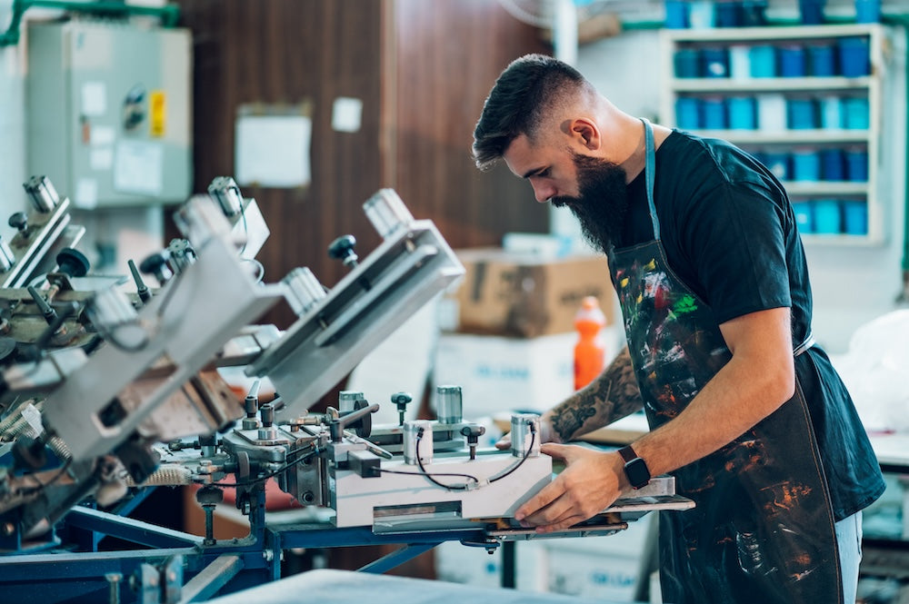 T shirt business owner using heat press in a shop